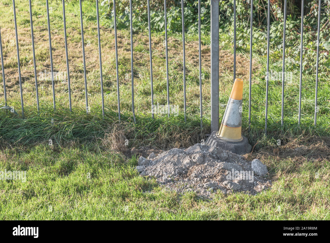 Cône orange et blanc road à côté du park l'escrime. Avertissement de sécurité Danger, métaphore, barrière, l'obstruction. Banque D'Images