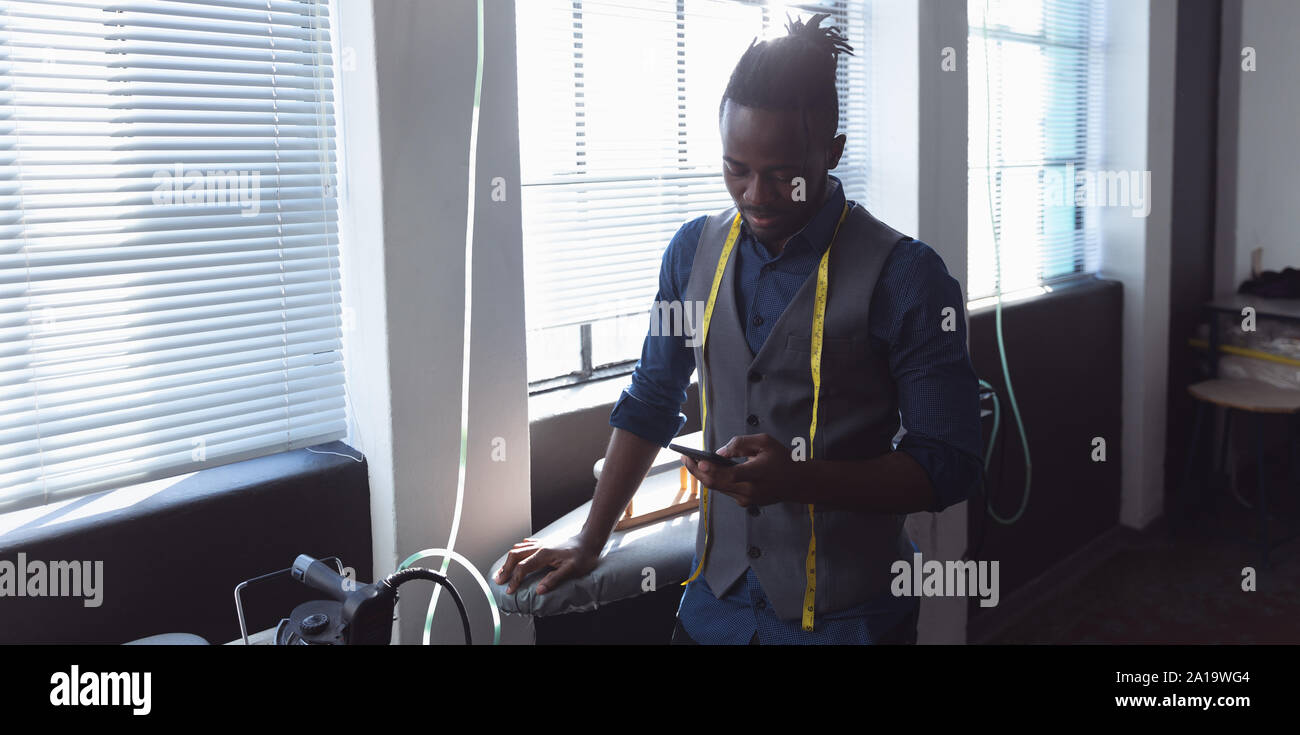 Male student using smartphone à une Fashion College Banque D'Images