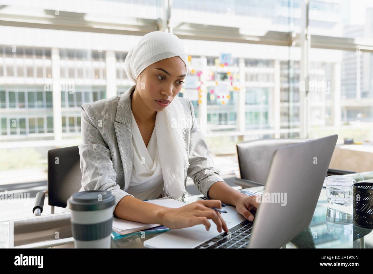 En hijab Businesswoman working on laptop at desk in a modern office Banque D'Images