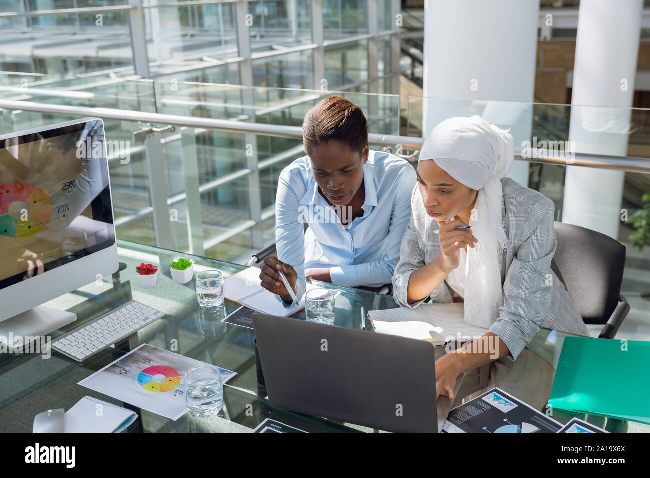 Les femmes executives discussing over laptop at desk Banque D'Images