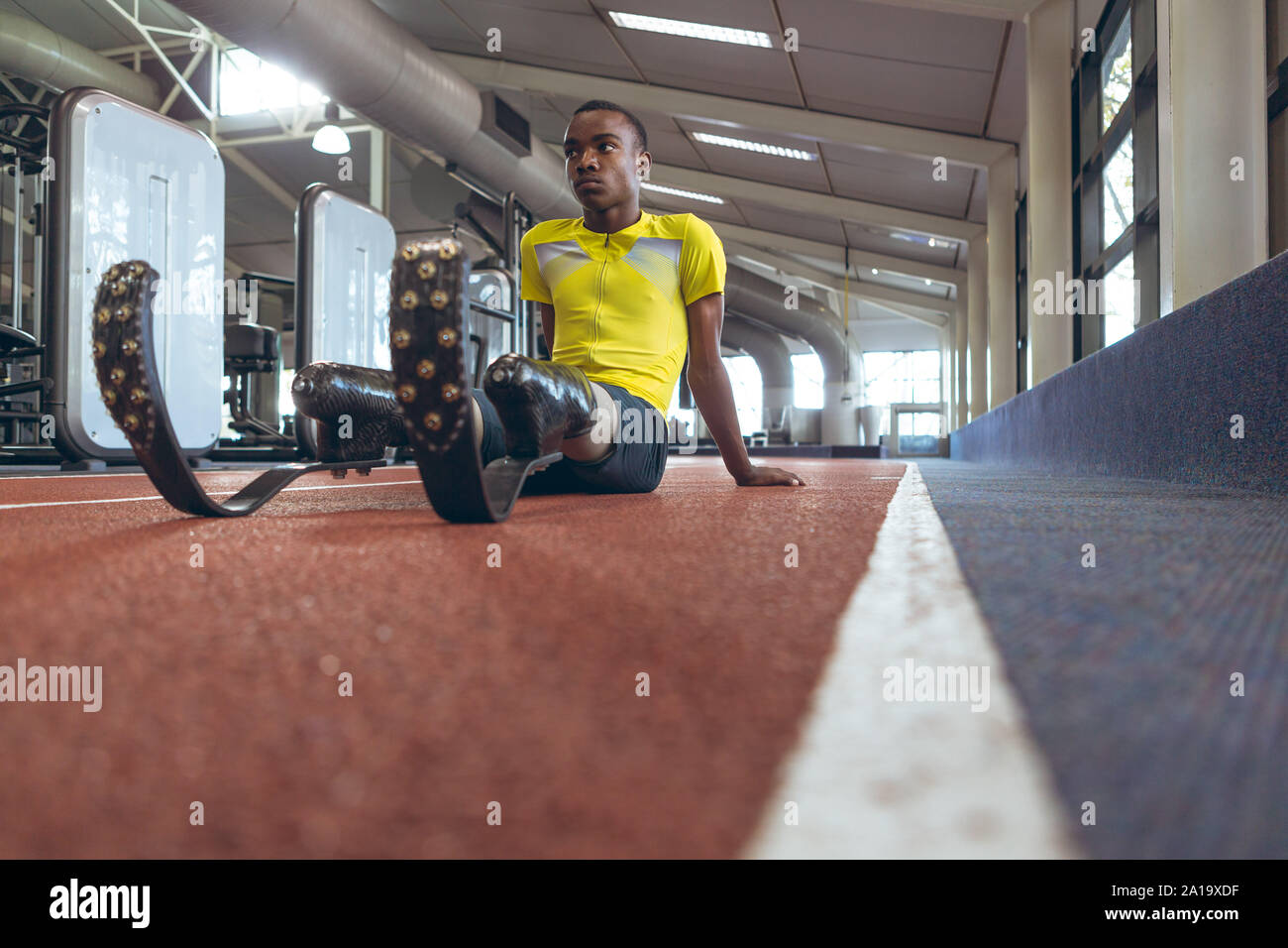 Mobilité African American male athletic détente sur une piste de course dans le centre de remise en forme Banque D'Images