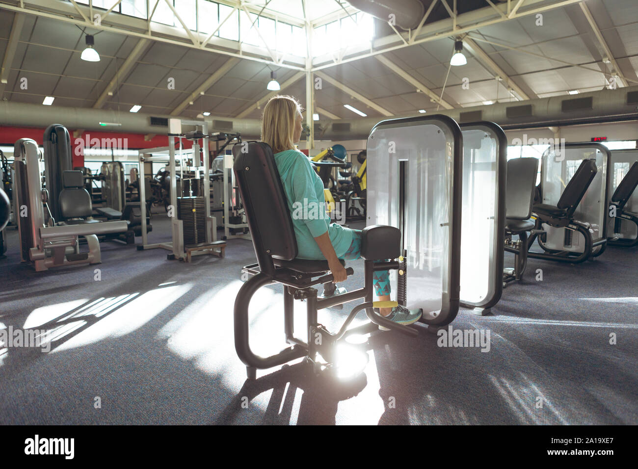 Mobilité active senior woman exercising with leg curl machine in fitness studio Banque D'Images