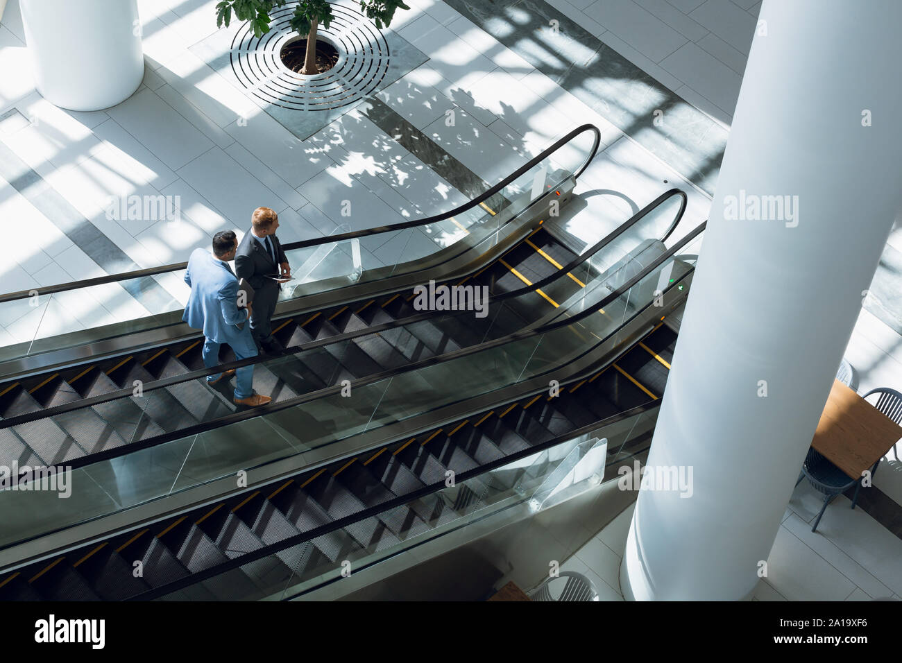 Hommes d'interagir les uns avec les autres tout en se déplaçant en bas sur escalator in office Banque D'Images