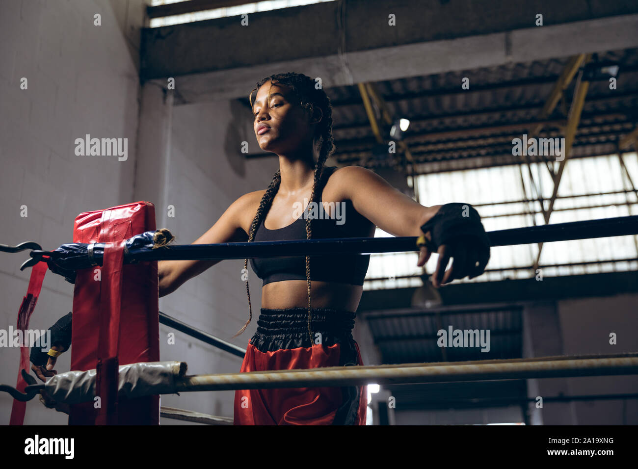 Boxer avec les yeux fermés s'appuyant sur des cordes en ring de boxe au club de boxe Banque D'Images