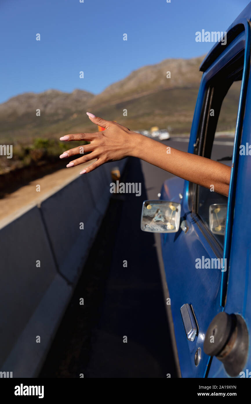 Jeune femme coller son bras hors de la camionnette sur la route Banque D'Images