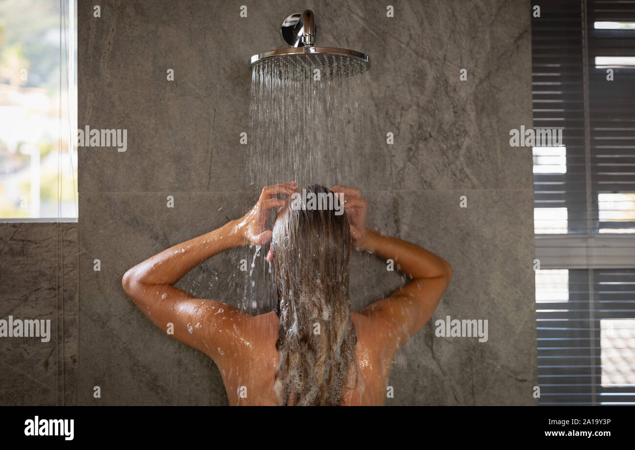 Jeune Femme prenant une douche dans une salle de bains moderne Banque D'Images