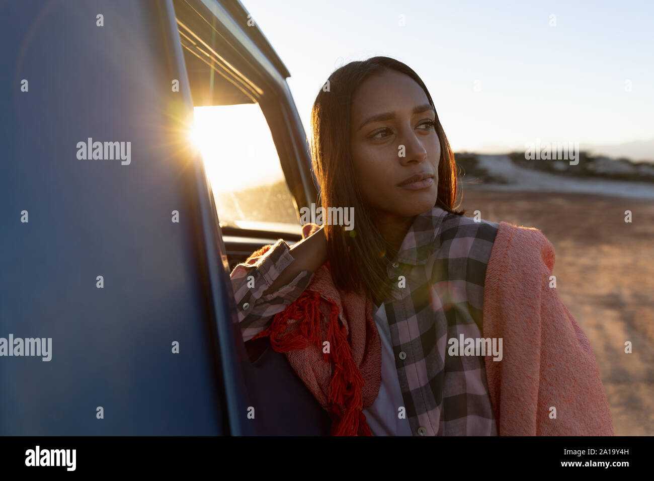 Jeune femme appuyée sur une camionnette lors d'un arrêt sur un voyage sur la route Banque D'Images