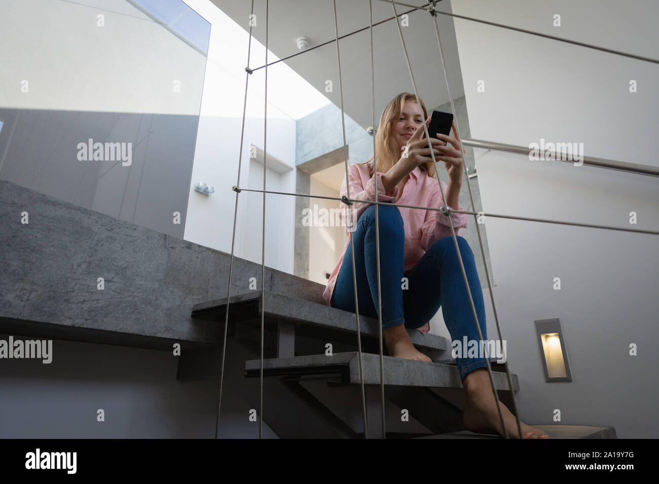 Jeune blonde sitting on stairs woman using smartphone Banque D'Images