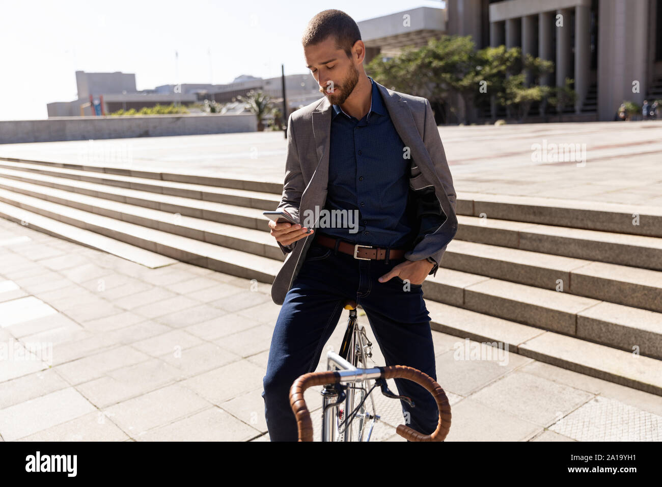 Jeune homme professionnel sur un vélo à l'aide du smartphone sur la rue Banque D'Images