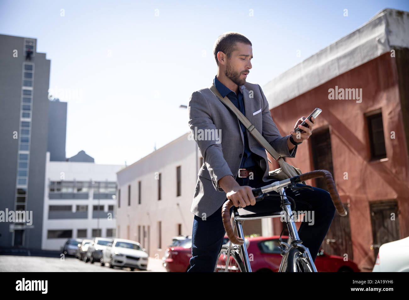 Young man using smartphone et assis sur le vélo Banque D'Images
