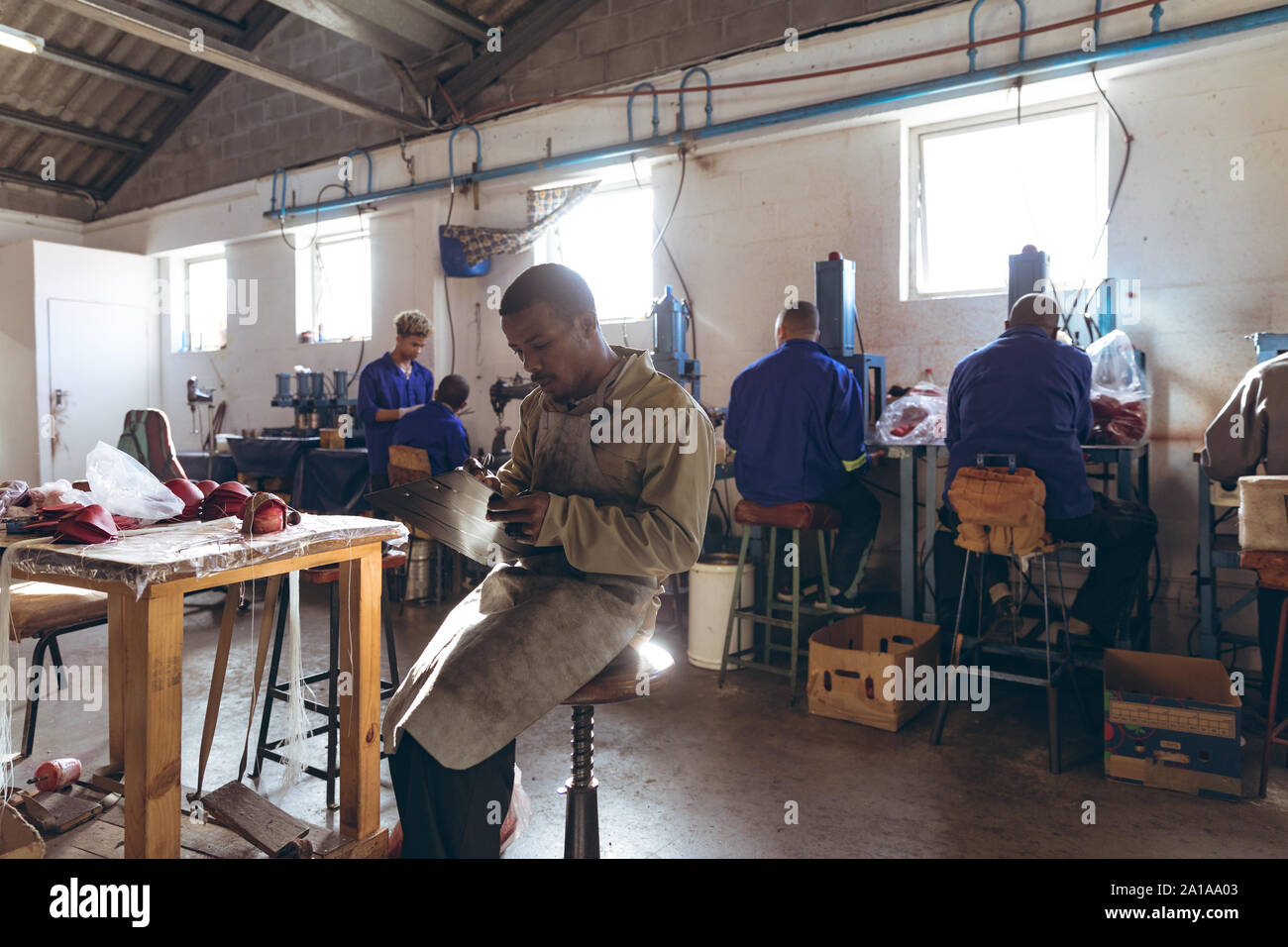 Jeune homme tenant un presse-papiers et l'écriture dans une usine de cricket ball Banque D'Images