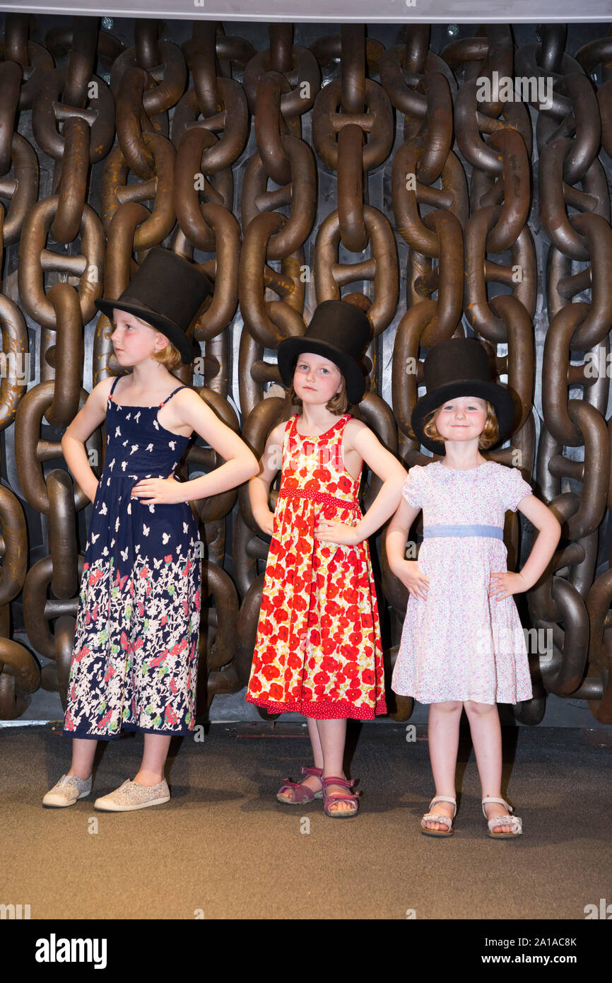 Trois sœurs enfants / kids / enfant / kid portant haut de forme et posent devant de grandes chaînes d'imiter la célèbre photographie d'Isambard Kingdom Brunel prises par Robert Howlett. Prises à l'exposition qui accompagne le Brunel SS Great Britain ship, Dockyard, Bristol England UK (109) Banque D'Images