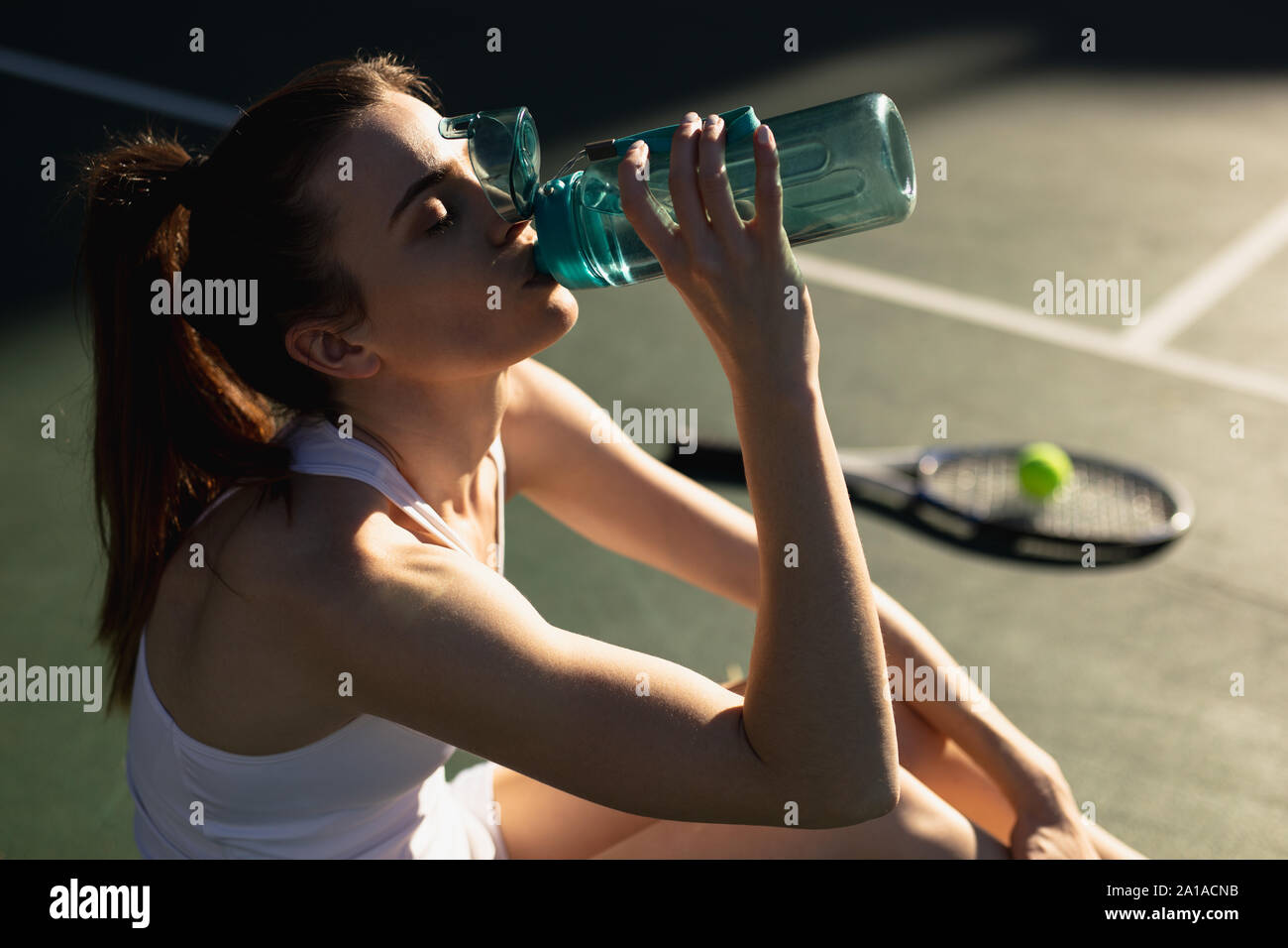 Femme l'eau potable au cours d'un jeu de tennis Banque D'Images