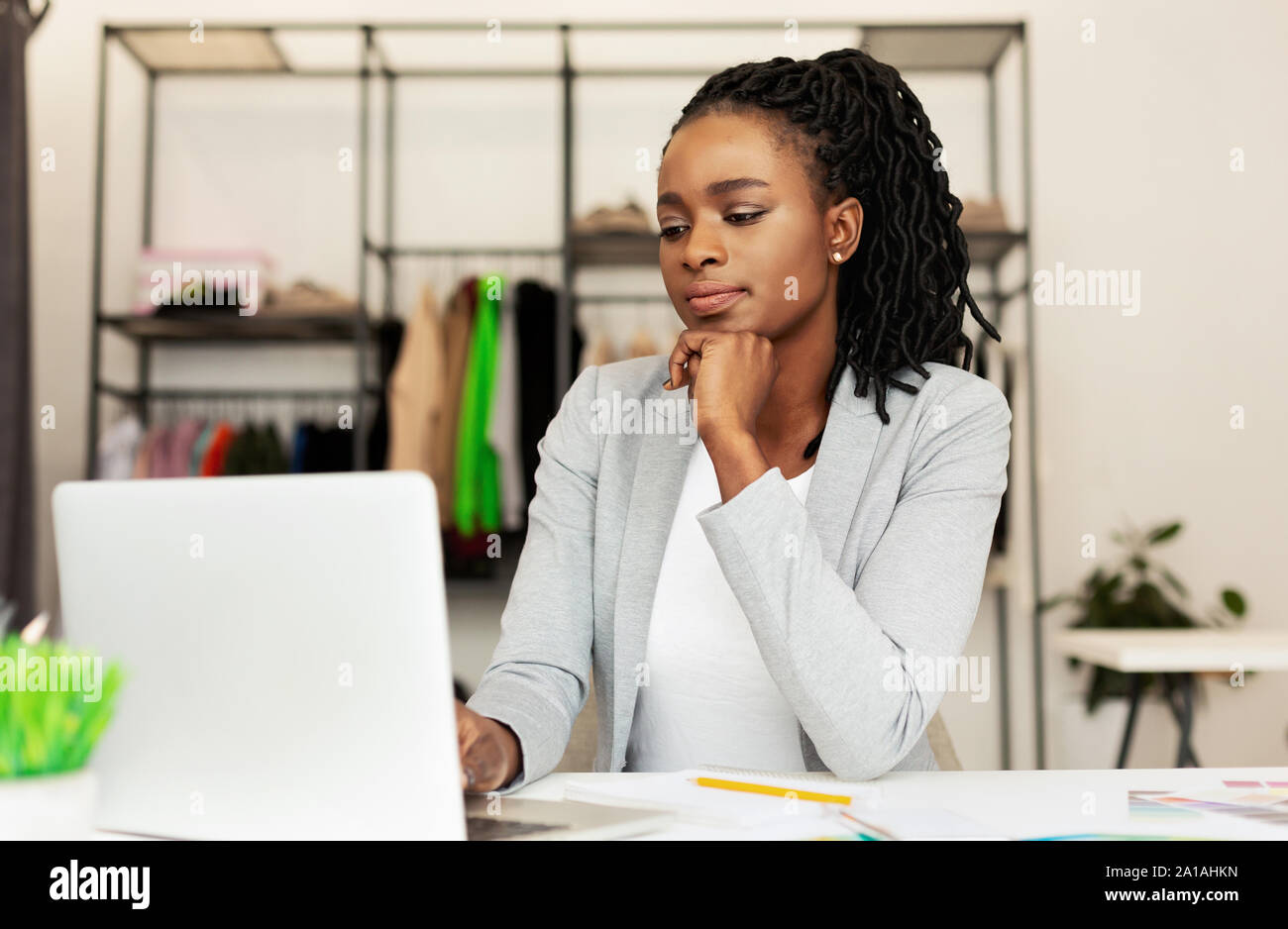 Les jeunes Afro Businesswoman Using Laptop In Clothing Store Banque D'Images