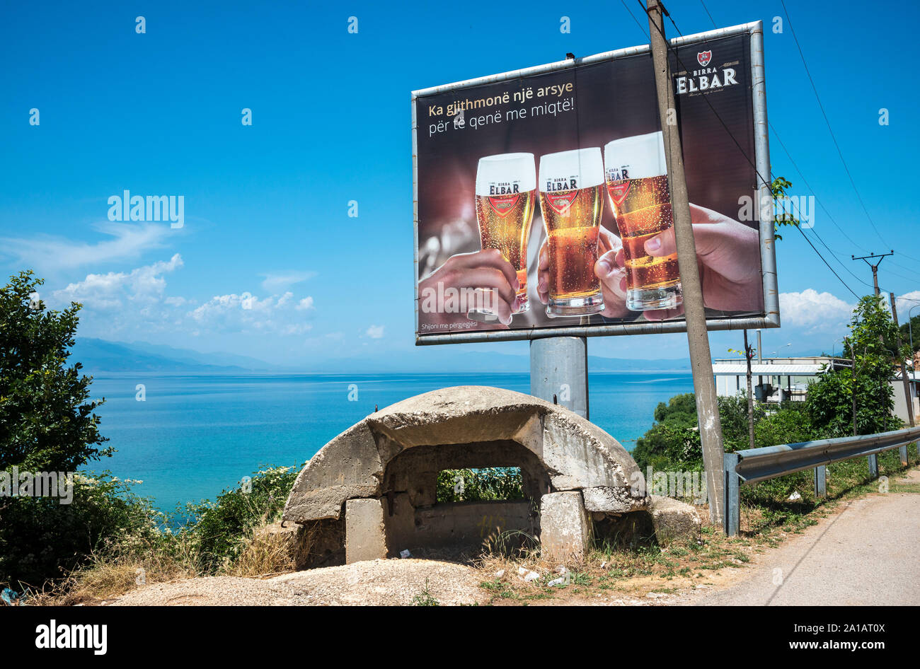 Période communiste abandonné casemate militaire et panneau publicitaire sur les rives du lac d'Ohrid à près de Tushemisht Pogradeci, sud-est de l'Albanie. Banque D'Images