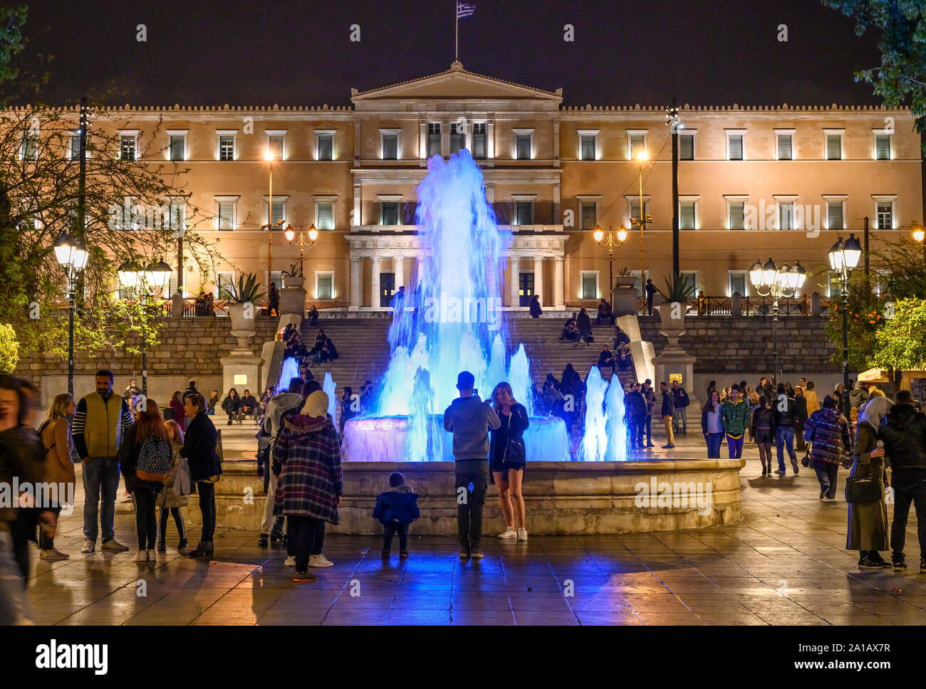 Profitant de la foule une promenade en soirée dans la place Syntagma à la Vouli, le parlement grec, dans l'arrière-plan, d'Athènes, Grèce. Banque D'Images