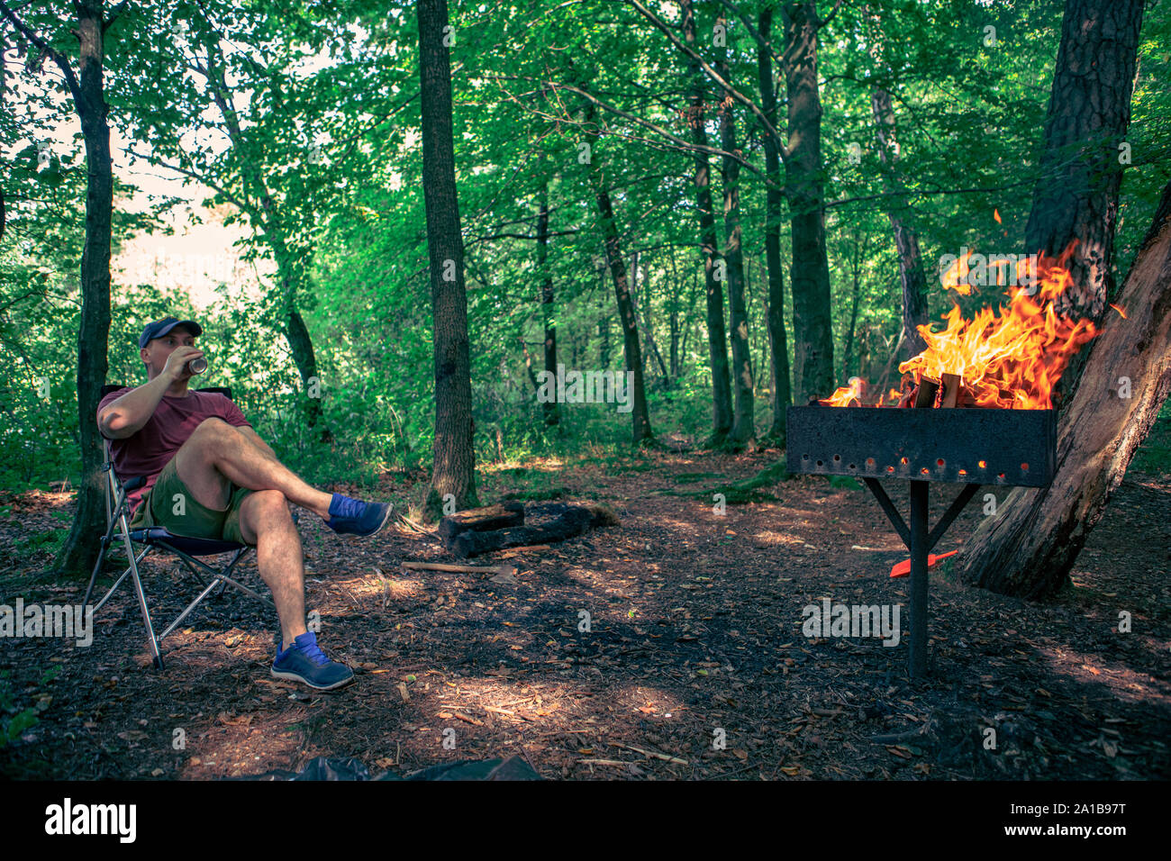 Homme assis en train de boire une bière président camp fire barbecue Banque D'Images