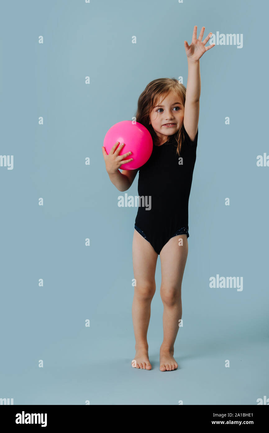 Petite fille dans un justaucorps noir rose avec ballon de gymnastique sur  fond bleu Photo Stock - Alamy