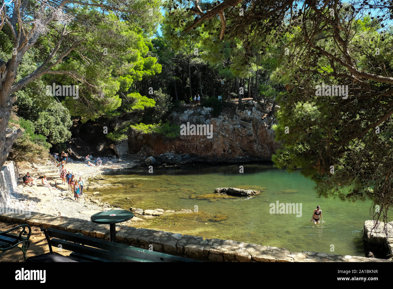 Une vue de la mer morte sur l'île de Lokrum, Croatie. Il y a un touriste dans l'eau avec d'autres marchant autour du bord de la piscine Banque D'Images