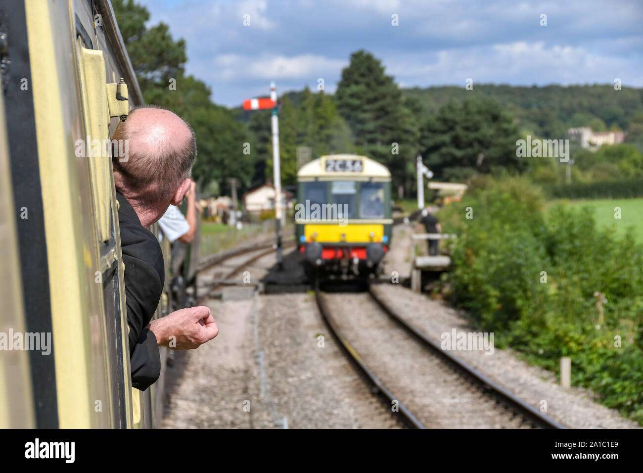 Gloucestershire, ANGLETERRE - SEPTEMBRE 2019 : fervent de train s'inclinant hors de la fenêtre d'un train pour voir un train diesel à unités multiples Banque D'Images