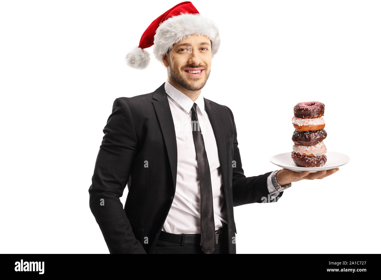 Jeune homme en costume holding a plate of chocolate donuts et wearing a Santa Claus hat isolé sur fond blanc Banque D'Images