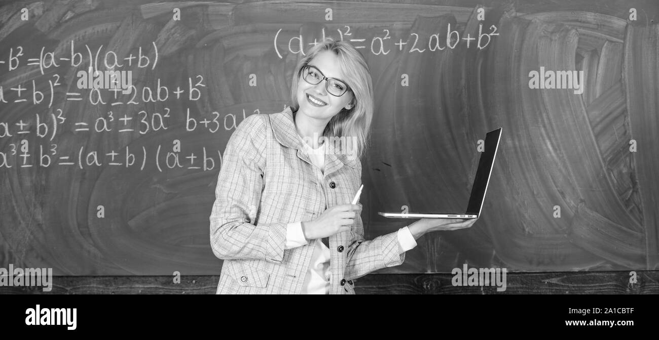 L'apprendre de manière simple. Enseignante portent des lunettes est titulaire d'ordinateur portable Internet surf. Dame intelligente smart éducateur avec ordinateur portable moderne tableau internet surf arrière-plan. Les technologies numériques concept. Banque D'Images