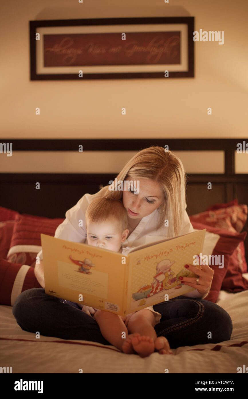 La lecture du livre de la mère à son bébé fille dans le lit Banque D'Images