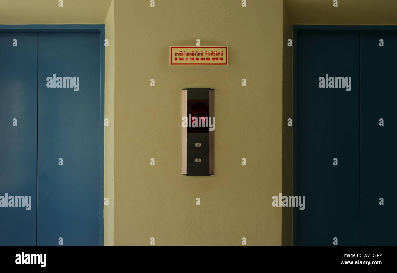 Bouton d'ascenseur avec affichage LED du panneau ci-dessus, il est rectangulaire signer lire en cas d'incendie, n'utilisez pas d'ascenseur dans les deux langues thaï et anglais Banque D'Images