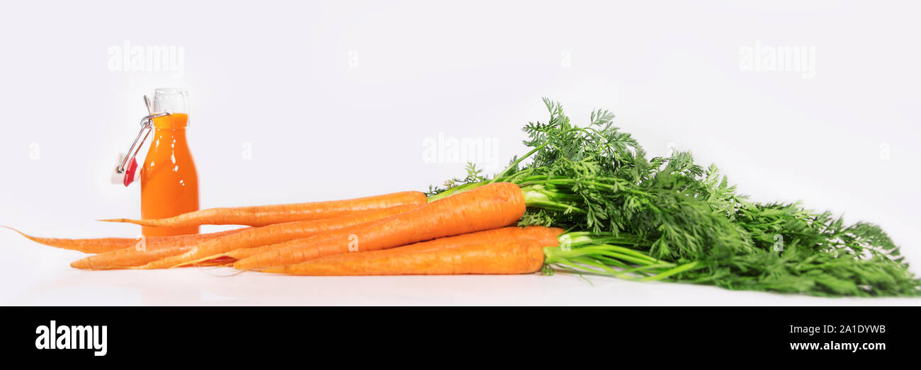 Panorama de carottes fraîches avec bouteille de jus sains devant un fond blanc Banque D'Images