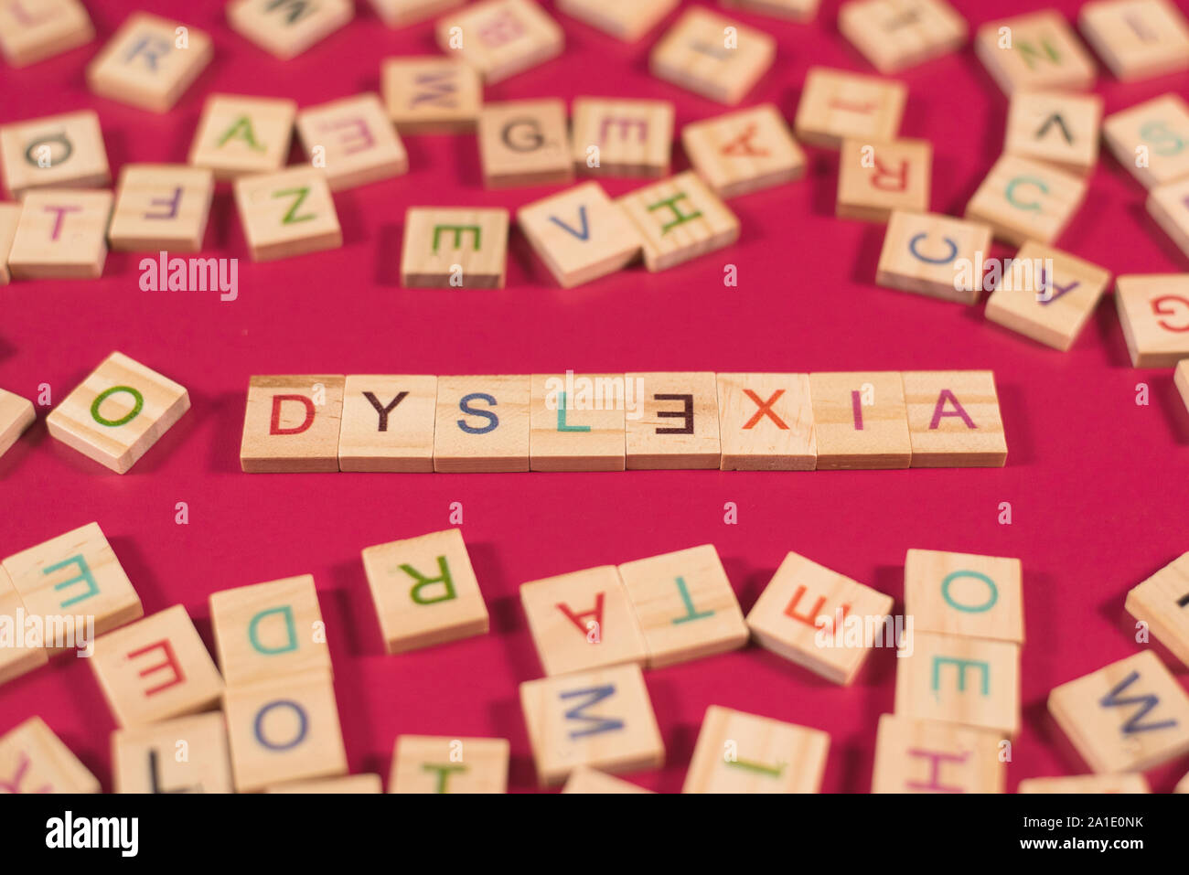 High angle view of a wooden alphabet blocks de dyslexie mot dans le centre sur fond rose. Concept de prise de conscience et la dyslexie cerveau humain développer Banque D'Images
