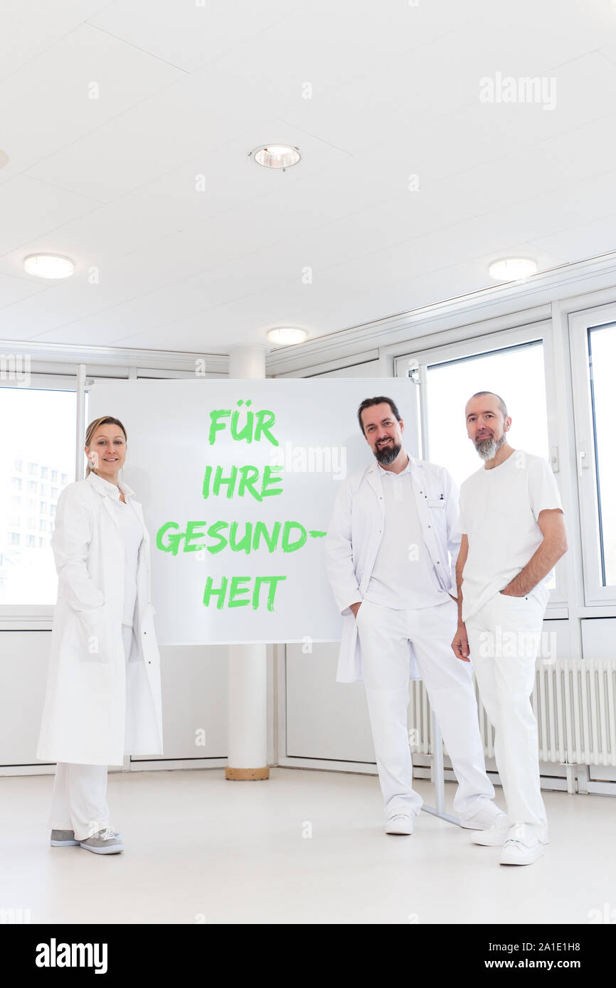 Les travailleurs de la médecine en face du tableau blanc avec texte allemand für ihre gesundheit, ce qui signifie pour votre santé Banque D'Images