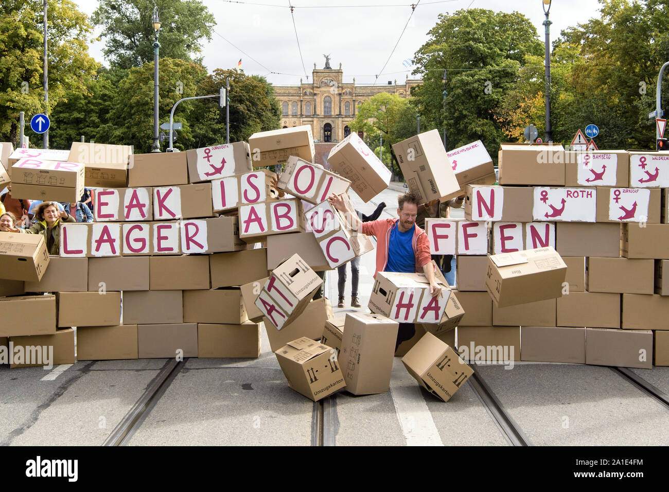 26 septembre 2019, Bavaria, Munich : les participants d'une action contre les centres d'abattre un mur de cartons de déménagement avec l'inscription 'briser l'isolement - Lager Abschaffen' et les noms des divers centres d'ancre en face de la parlement bavarois. La raison de l'action est une audition d'experts sur les centres d'ancrage dans le Parlement de Bavière. Le Conseil des réfugiés de Bavière, réfugiés lutte pour la liberté, la caravane Munich et anker-watch.de la demande avec leur action sous la devise 'briser l'isolement ! D'autres auditions d'experts dont les réfugiés ont également leur mot à dire. Photo : Matthias Balk/dpa Banque D'Images