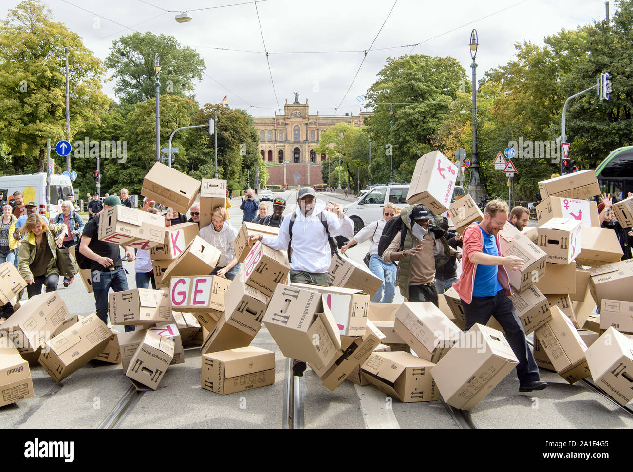 26 septembre 2019, Bavaria, Munich : les participants d'une action contre  les centres d'abattre un mur de cartons de déménagement avec l'inscription  'briser l'isolement - Lager Abschaffen' et les noms des divers