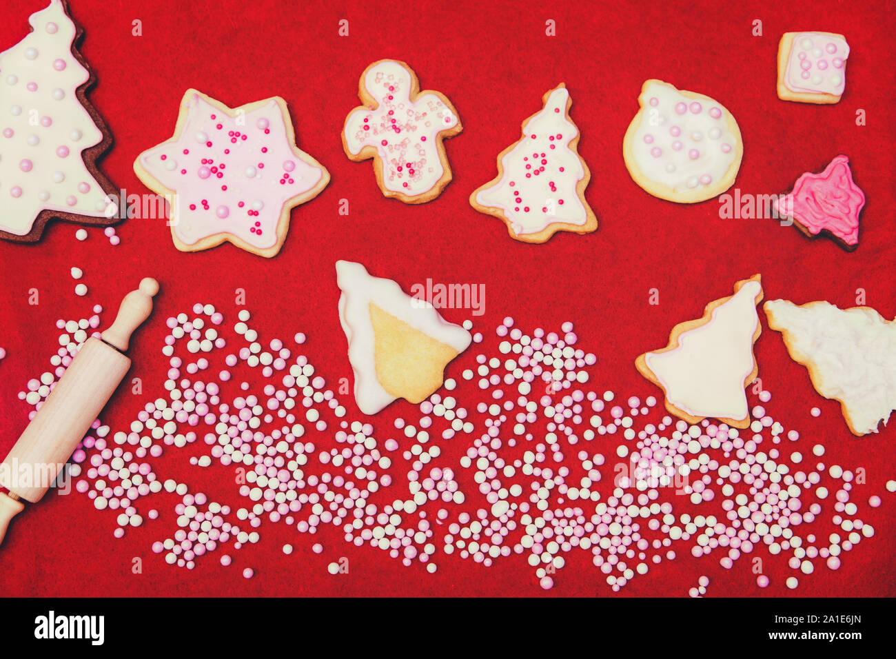 De savoureux biscuits de Noël avec le glaçage royal et perles de sucre et de pâte rouleau, fond rouge Banque D'Images