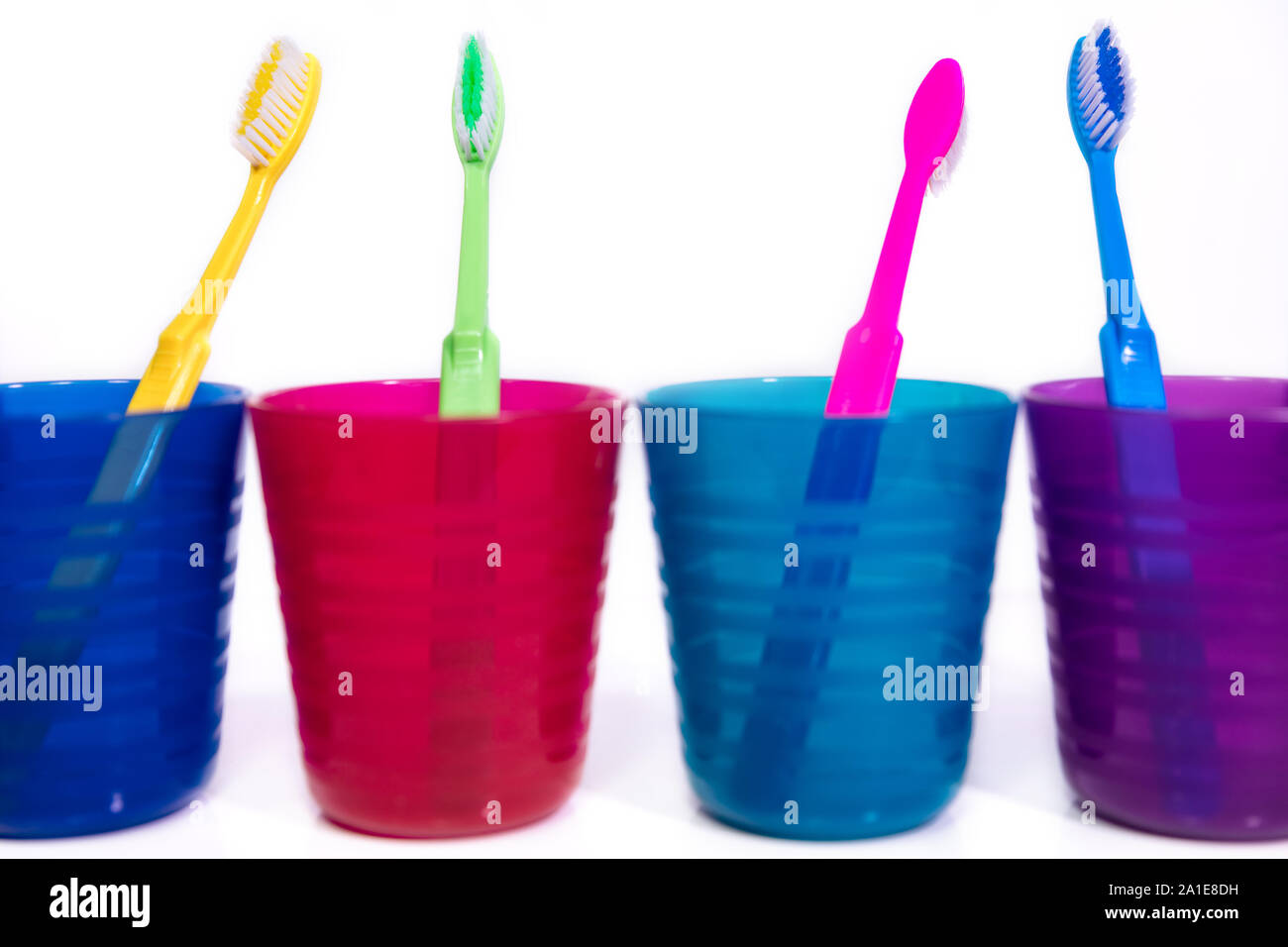 Quatre tasses colorées avec des brosses à dents, fond blanc, de soins dentaires et d'hygiène concept Banque D'Images