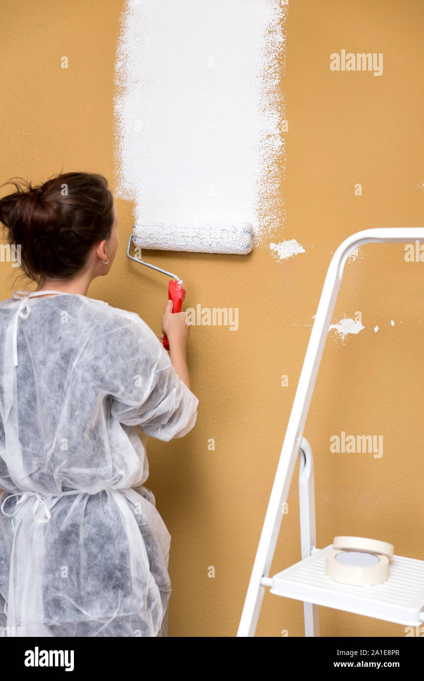 Travaux de rénovation à la maison, jeune femme peindre un mur en blanc Banque D'Images