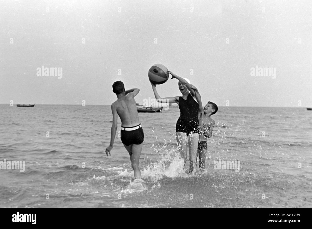 Eine junge Frau mit zwei tobt Jungen und einem Wasserball im Meer, Deutschland 1939. Une jeune femme et deux garçons contre dans l'eau, de l'Allemagne 1939. Banque D'Images