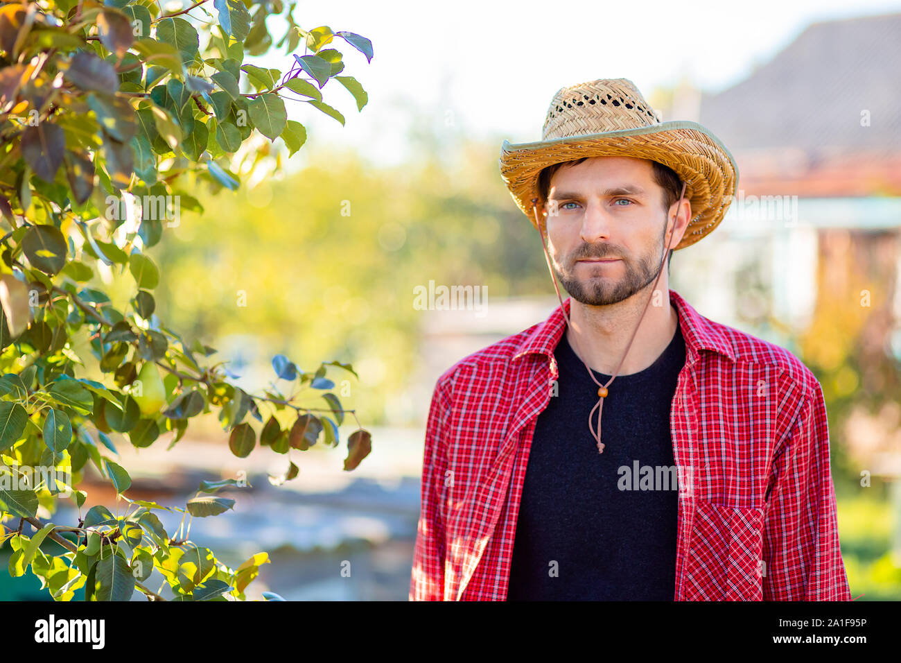 Beau cowboy, portrait d'un agriculteur dans son jardin. Un homme dans un chapeau de cowboy. Banque D'Images