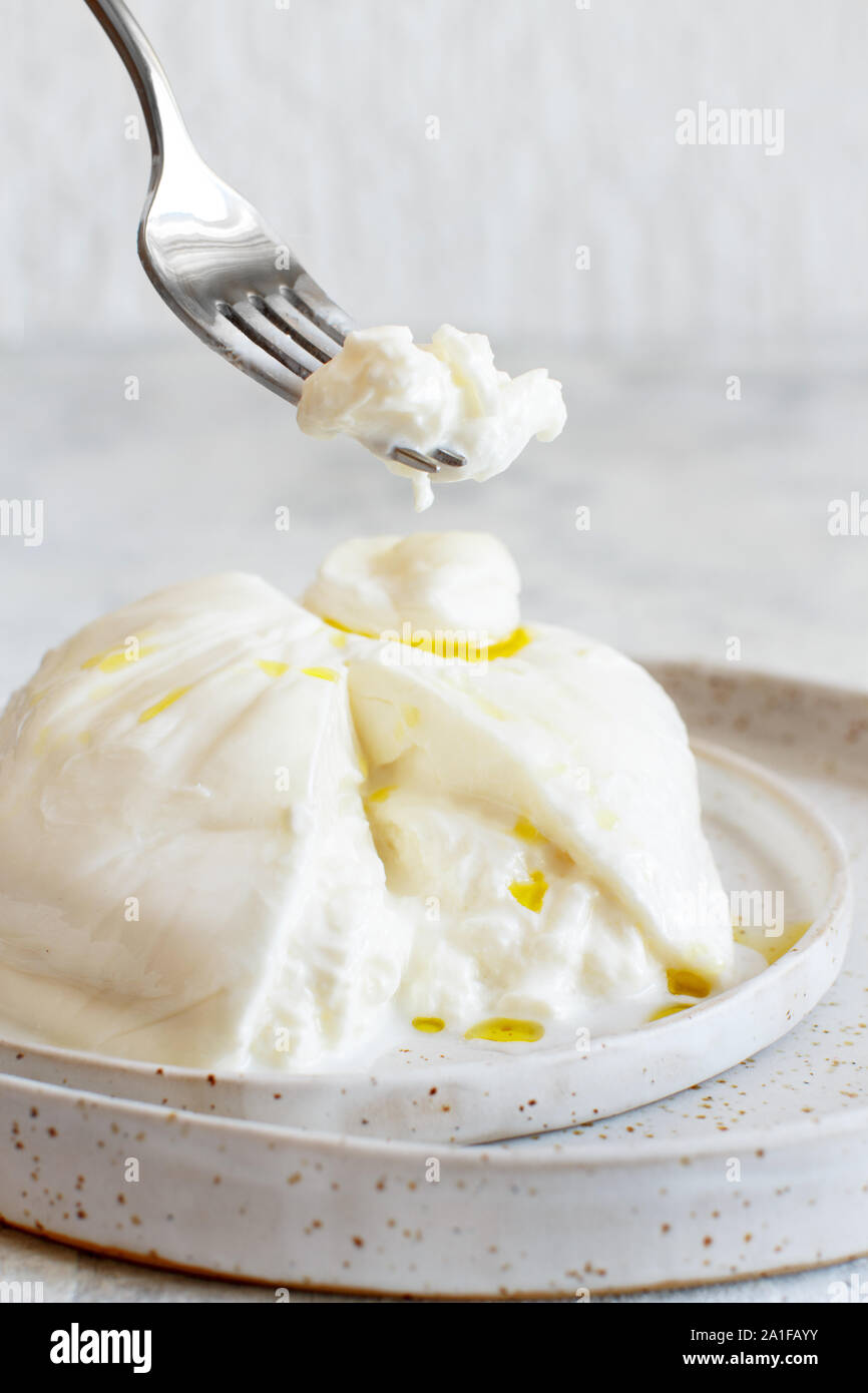 Burrata fromage italien sur une assiette avec une fourchette jusqu'cloes Banque D'Images