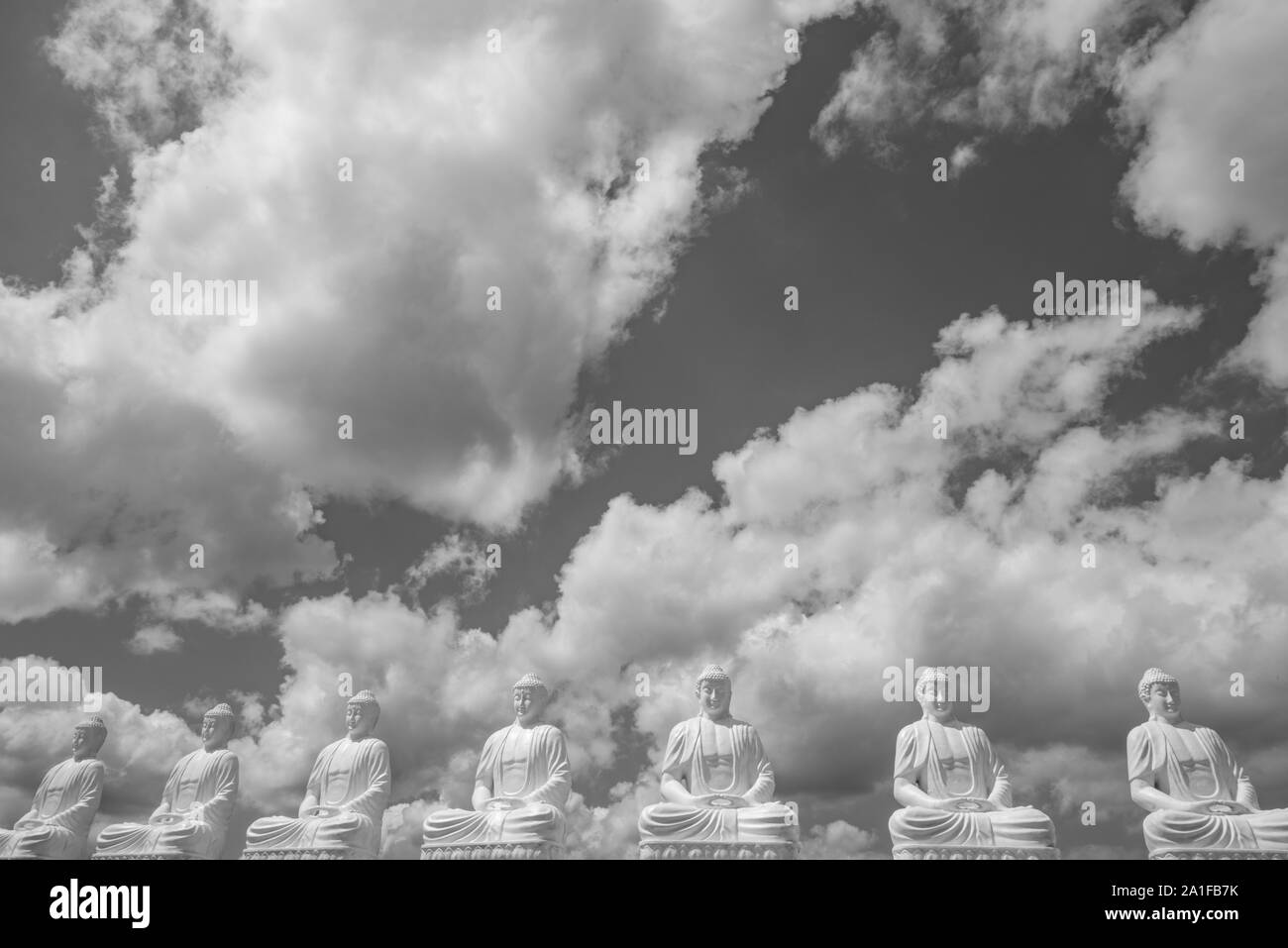 Statues de Bouddha en rangée, sous ciel nuageux Banque D'Images