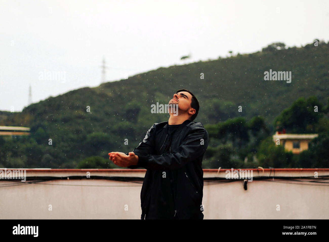 Jeune homme de jouer et profiter de la pluie. Garçon s'amuser sous les gouttes d'eau. Banque D'Images