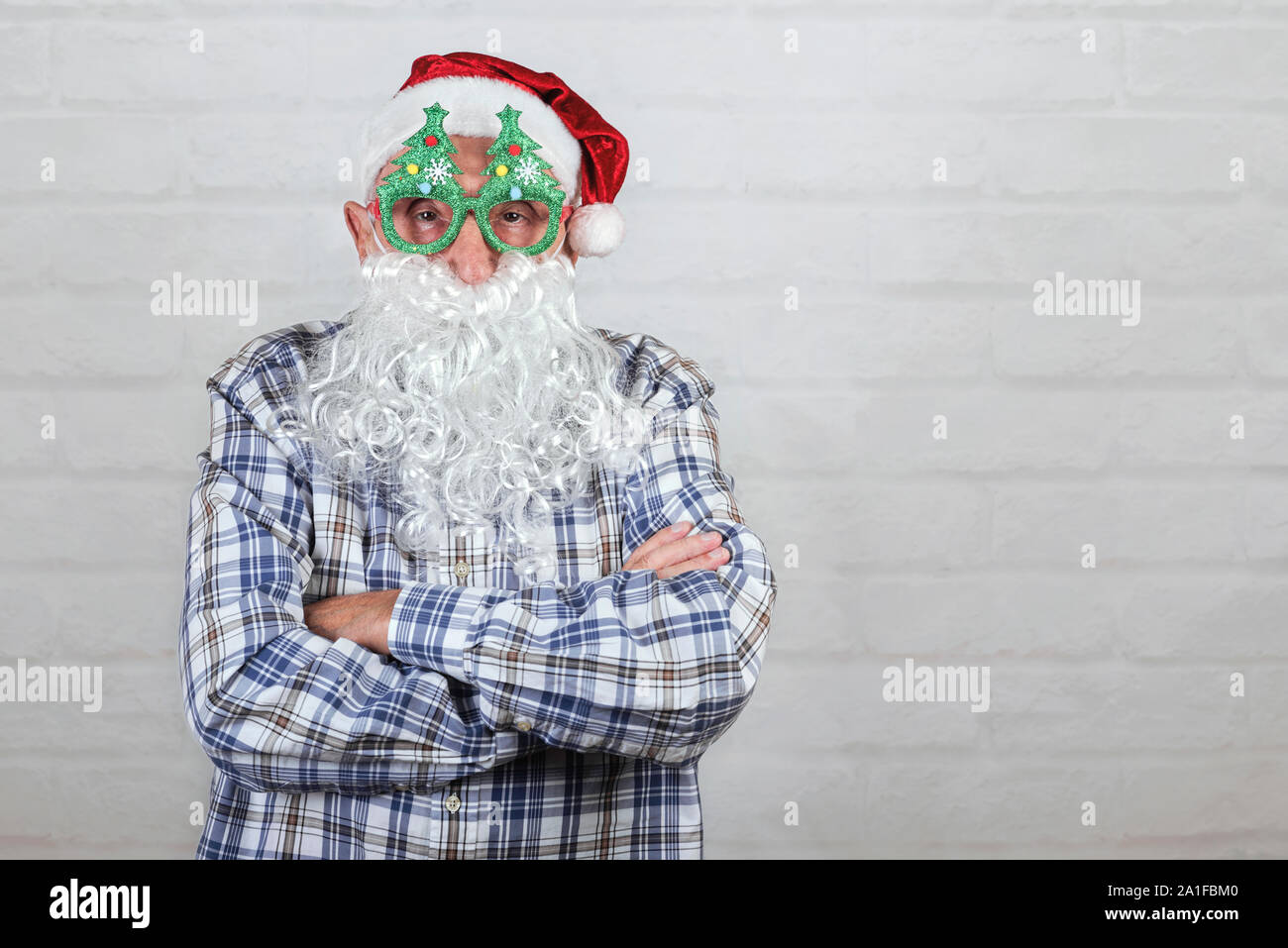 Grand-père Wearing Christmas Santa Claus Hat et beard sur fond brique Banque D'Images