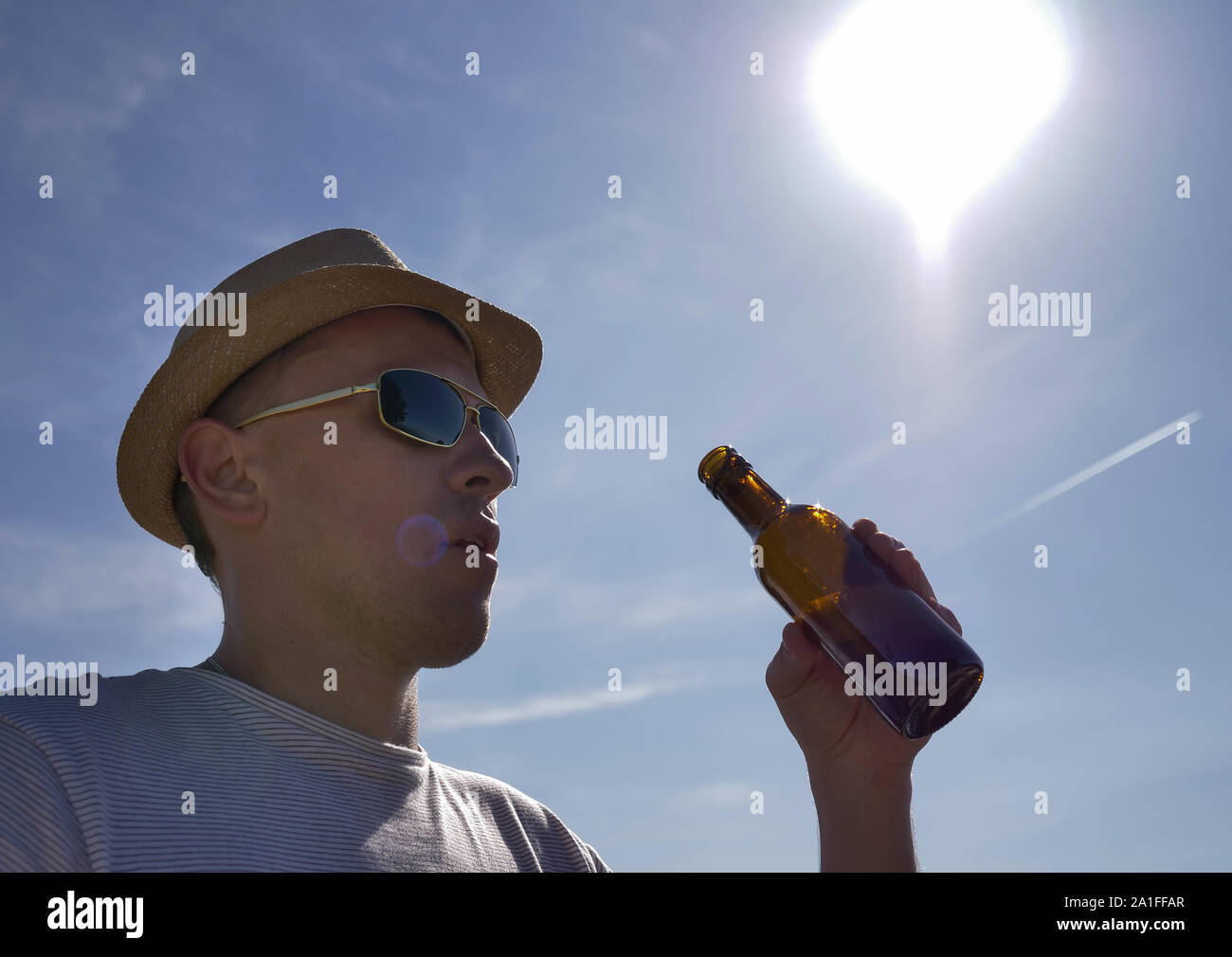 Young man in hat veut boire une bière rafraîchissante d'une bouteille à l'extérieur Banque D'Images