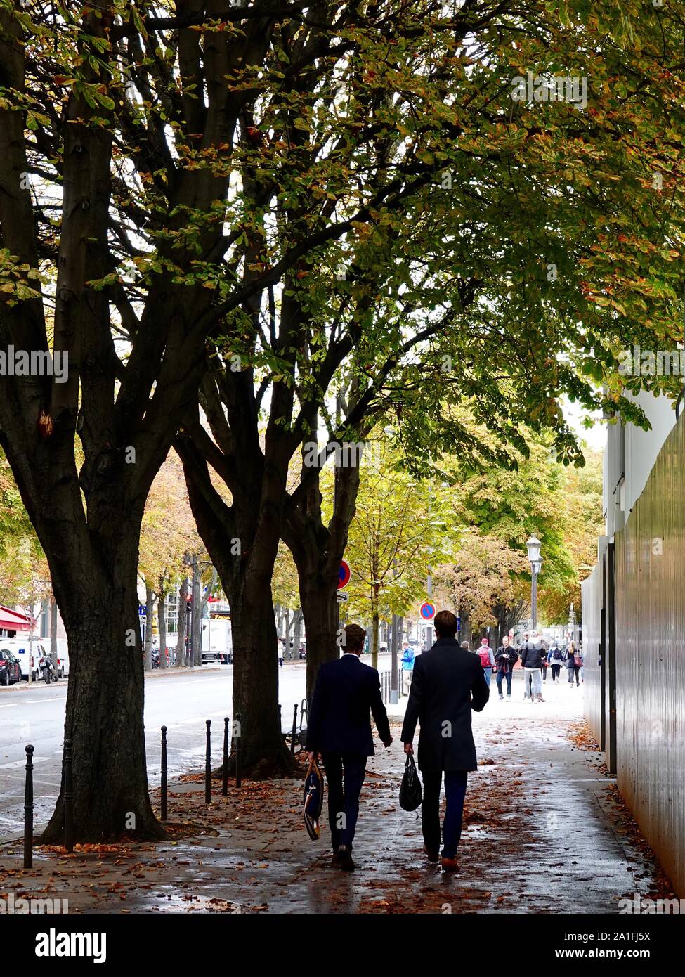 Les Français en tenue de voyage d'affaires, vu de l'arrière, marchent sur le trottoir le long de l'avenue Franklin Delano Roosevelt dans le 8ème arrondissement, Paris, France. Banque D'Images