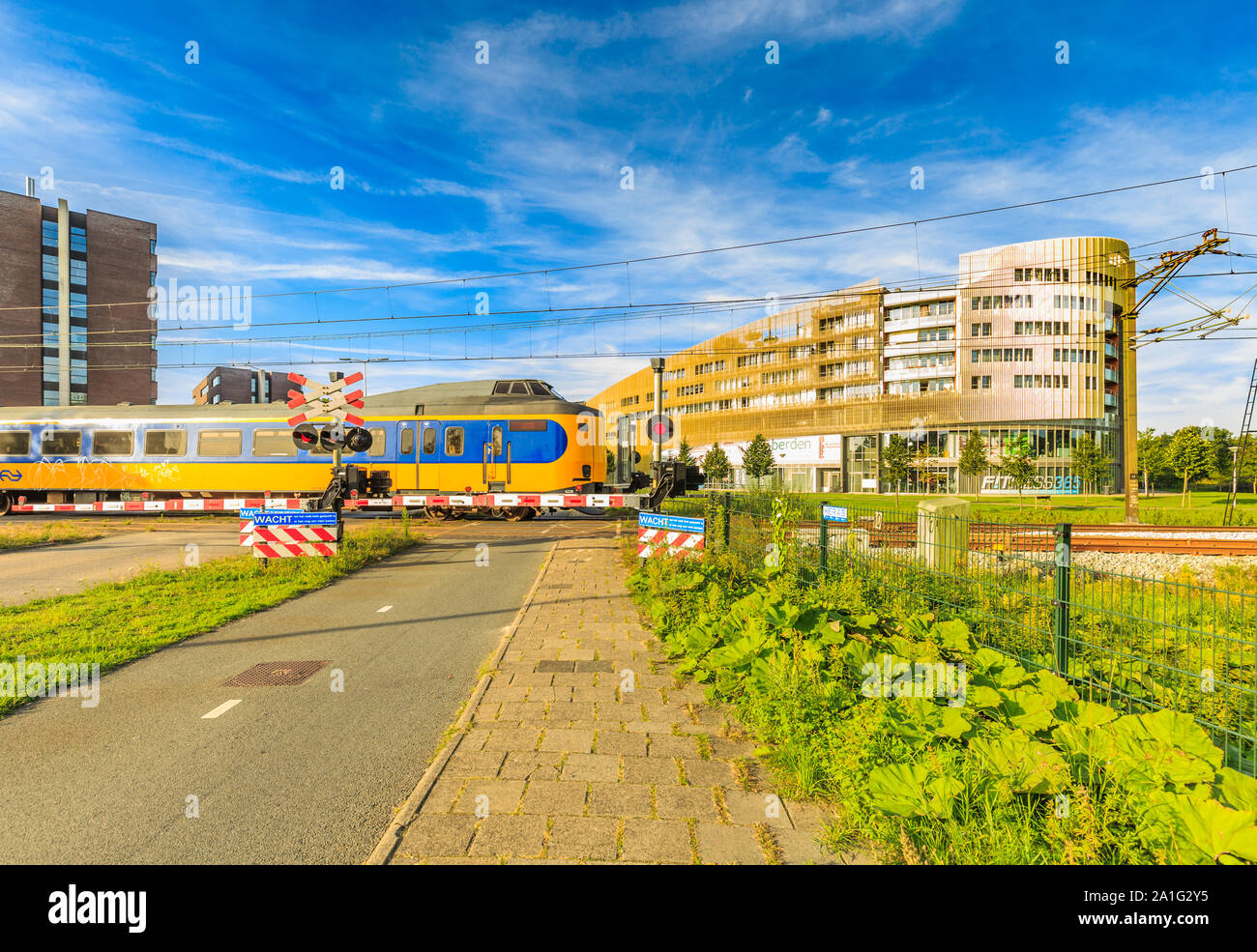 Laan der Continenten, Alphen aan den Rijn, Zuid Holland, les Pays-Bas, le 23 août 2019 : passage à niveau des chemins de fer néerlandais et de train qui passe, fermé Banque D'Images