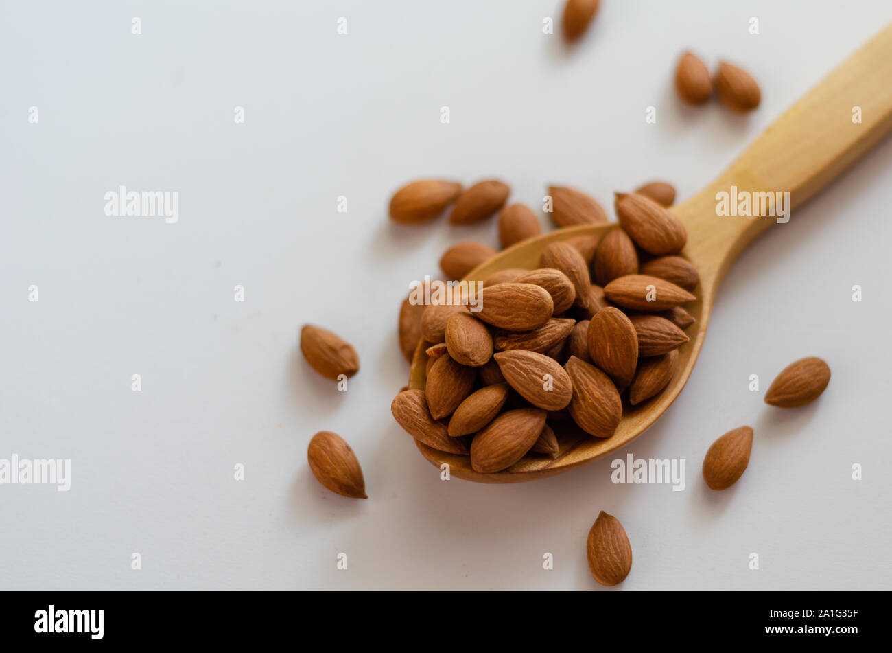 Les écrous d'amandes séchées en cuillère en bois sur fond blanc.amandes Pelées. Banque D'Images