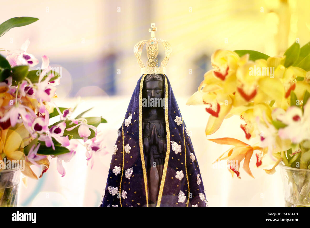 Statue de l'image de Notre Dame d'Aparecida, Mère de Dieu dans la religion catholique, Patronne du Brésil, décorées avec des fleurs et des orchidées Banque D'Images