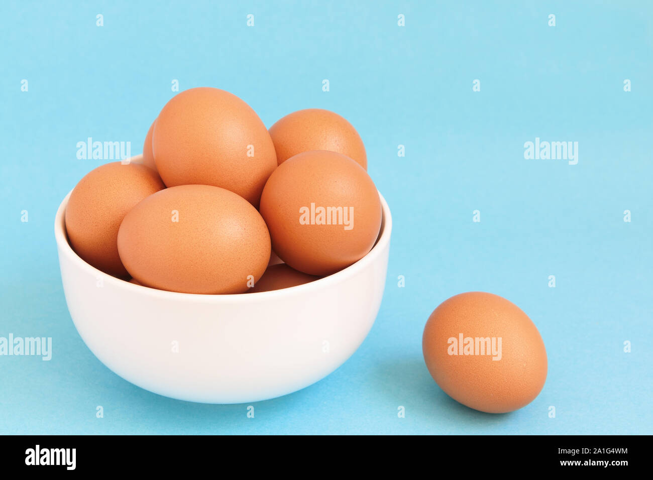 Brown frais oeufs de poule dans le bol blanc sur fond bleu clair Banque D'Images