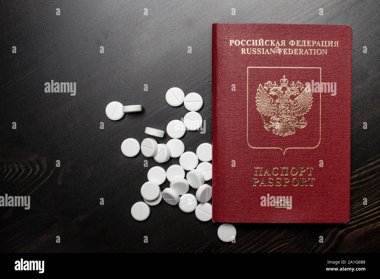Passeport de citoyen de la Fédération de Russie est sur une table en bois à côté de pilules médicaux éparpillés Banque D'Images