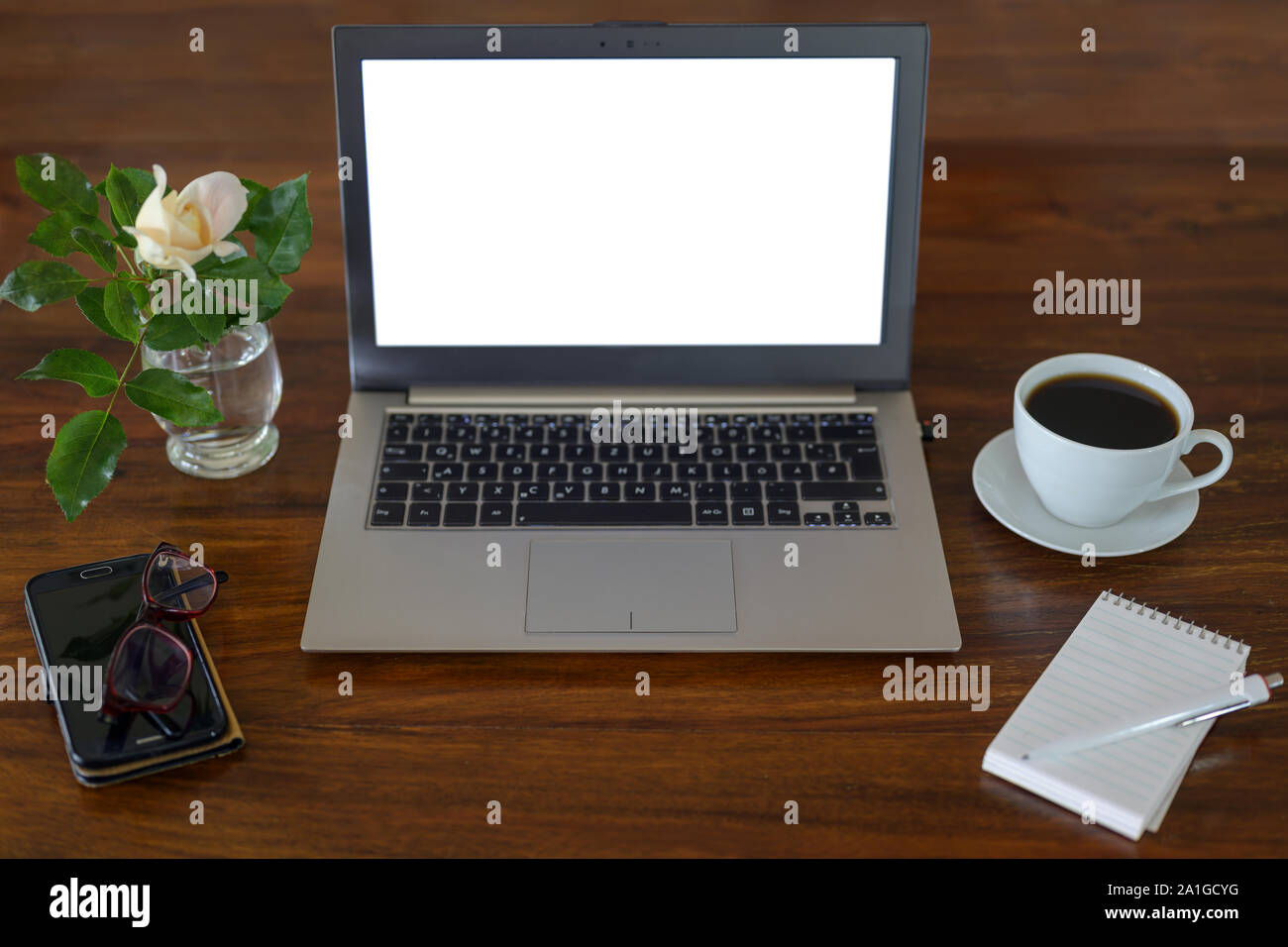 Des maquettes, ordinateur portable avec écran blanc sur un bureau en bois avec le bloc-notes, verres, tasses à café, téléphone et une fleur, business espace de travail dans un bureau, copie Banque D'Images
